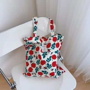 Vintage floral cotton tote bag with red roses and white label on a minimalist chair