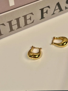 Detailed macro shot of golden U-shaped tulip earrings with high polished metallic finish