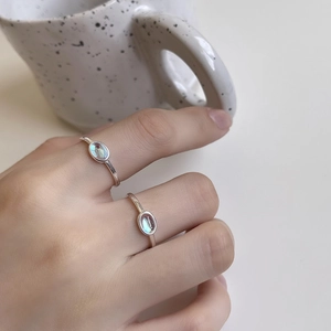Detail of 925 sterling silver rings featuring oval rainbow stones worn on fingers