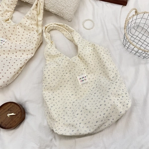 Detail of floral corduroy tote bag featuring a brand label and striped texture fabric