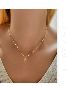 Macro shot of gold cross necklace with colorful beads and center zircon on neck