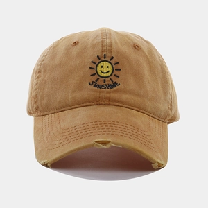 Detail of sunshine embroidery and distressed brim on washed khaki baseball cap