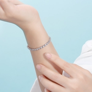 Detailed close-up of a silver tennis bracelet with round cubic zirconia on a wrist