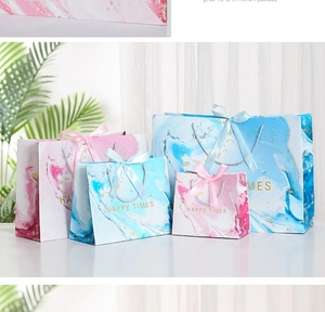 Detail view of marble pattern gift bags with ribbon handles and gold HAPPY TIMES text