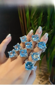 Detail of square aquamarine topaz rings with pavé diamond setting on model hand