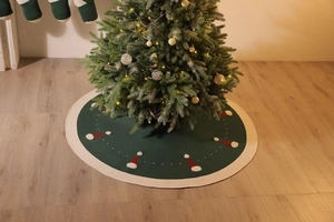 Détail du tapis de sapin de Noël tricoté vert avec bonnets rouges et bordure peluche