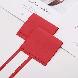 Macro detail of red velvet jewelry envelope pouch with ribbon tie on minimalist background