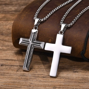 Detailed comparison of textured and smooth stainless steel cross pendants on leather book