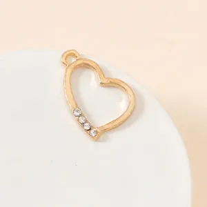 Macro detail of a heart-shaped gold plated alloy pendant with small diamond accents