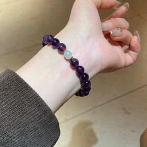 Detailed shot of amethyst beaded bracelet with green accent stone and golden spacers