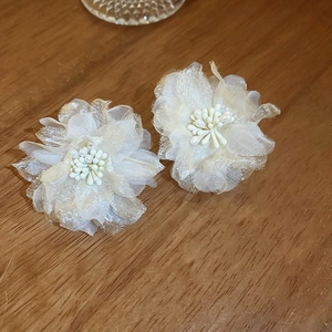 Detailed view of handmade cream lace flower earrings with layered petals and beaded stamen