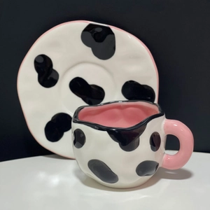 Detail of pink-trimmed irregular ceramic coffee cup and saucer with cow print pattern