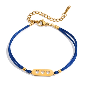 Gros plan du bracelet tressé bleu royal avec trois breloques en forme de cœur évidé en or 18 carats