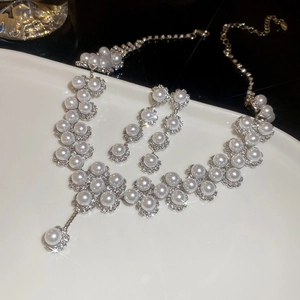 Elegant floral pearl necklace and earrings jewelry set with diamonds on a white display