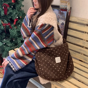 Detail of plush brown polka dot tote bag with brand label in cozy Christmas setting