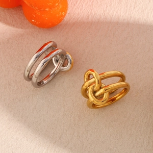 Detail of interlocking two-tone knotted rings in 18K gold and silver stainless steel