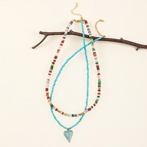 Double-layer beaded necklace with heart pendant hanging on a natural wooden branch