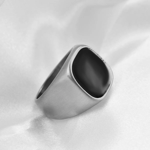 Detailed close-up of matte silver signet ring with square black enamel inlay on silk