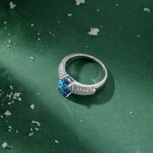 Macro shot of silver ring with blue round gemstone and double row pave-set crystals
