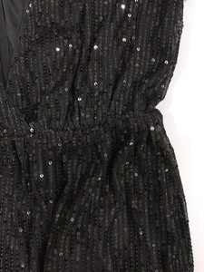 Dettaglio di paillettes nere cucite su rete con pieghe in vita del vestito elegante