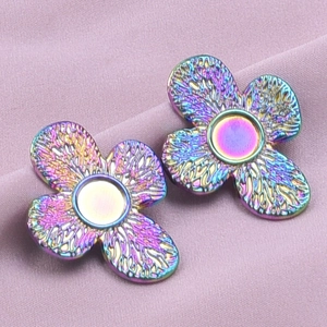 Detailed macro view of rainbow iridescent stainless steel flower earrings on purple fabric
