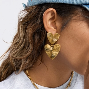 Chic gold stainless steel double heart studs with radial texture on a female model