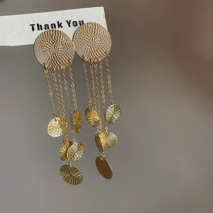 Detail of golden tassel earrings with spiral textures and small circular metallic plates