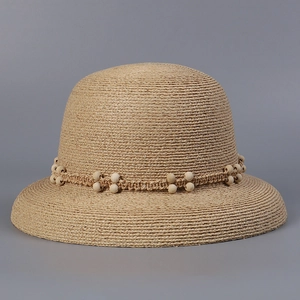 Detail of raffia straw hat with hand-woven band and wooden beads decoration