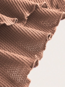 Close-up of brown waffle knit fabric with detailed ruffles and textured finish