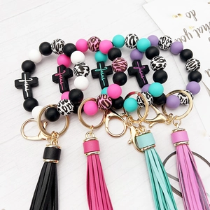 Silicone beaded cross keychain bracelet with Jesus charm and colorful tassels on wood surface