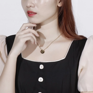 Close-up of model wearing a gold round pendant necklace with letter C engraving
