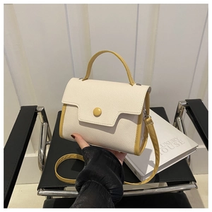 Detail of the cream leather handbag with contrasting yellow handles on a black chair