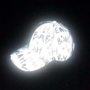 Detail of reflective baseball cap with black graffiti letters glowing under flash light