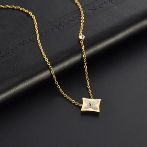 Macro shot of gold square pendant featuring shell flower inlay and sparkling crystal detail