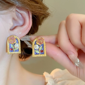 Macro detail of French vintage rose earrings with pearls and purple enamel finish