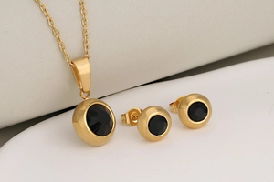 Detailed set of gold necklace and stud earrings with round black birthstones