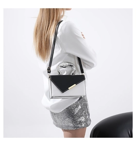Detail of a color-block crossbody bag featuring a silver heart-shaped metal handle and flap