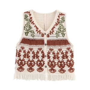 Detail of bohemian crochet vest with floral embroidery and decorative bottom fringe
