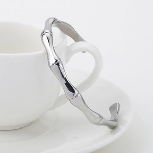 Gros plan d'un bracelet ouvert en acier inoxydable argenté sur une tasse blanche
