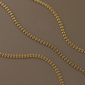 Macro shot of three minimalist gold-plated wheat necklaces in various craft designs