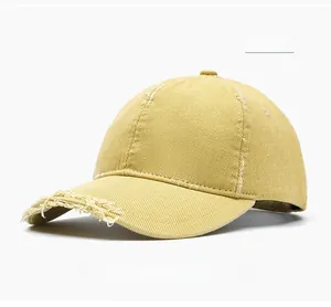 Detail view of yellow distressed cotton baseball cap with vintage frayed brim style