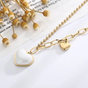 Detailed view of gold double-layer necklace with pearl heart and small gold heart pendants