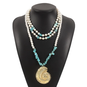 Detail of bohemian layered necklace with white pearls, turquoise and gold conch pendant
