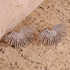 Close-up of silver stainless steel fan-shaped stud earrings on stone texture