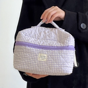 Vista dettagliata della borsa da trucco trapuntata a quadretti viola con manico