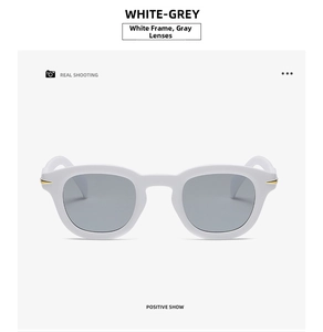 Detailed close-up of white sunglasses frame with grey lens and gold rivet detail