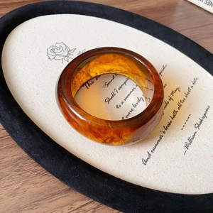 Macro view of vintage amber resin bangle with marbled texture on a retro tray