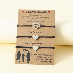Close-up of three black cord bracelets with silver heart pendants on a 3 generations card