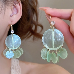 Detail of light green shell drop earrings with zircon studs and hanging discs