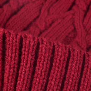 Thick red knit beanie featuring classic cable patterns and ribbed texture for winter warmth